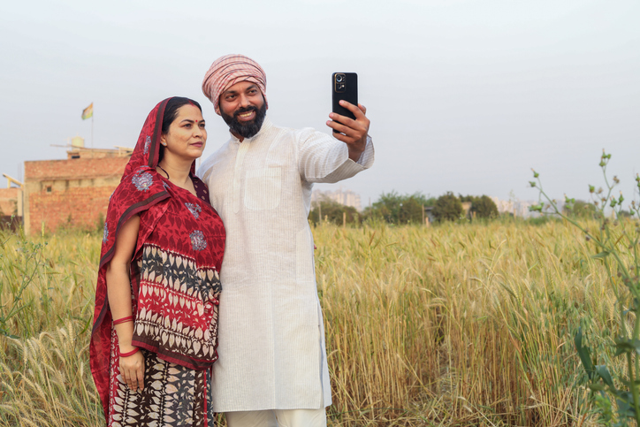 Indian couple in agriculture field in rural India. Wireless technology, 5G network.